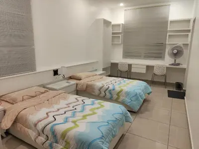 a bedroom with two beds and a desk and a window at Prestij 3 Homestay, Balik Pulau in Balik Pulau