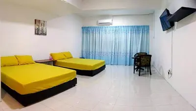 two beds in a room with yellow sheets at “Alan Homestay” Pangkor Lot 10 in Kampong Sungai Udang