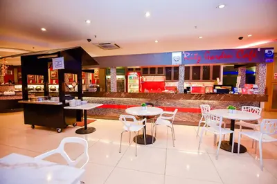 a restaurant with tables and white chairs and a counter at Ritz Garden Hotel Manjung in Lumut