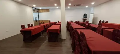 a conference room with red tables and chairs and a podium at Hotel Damai in Parit Buntar