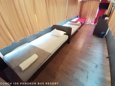 two beds in a room with curtains and wood floors at Pangkor Bus Resort by BESLA in Pangkor