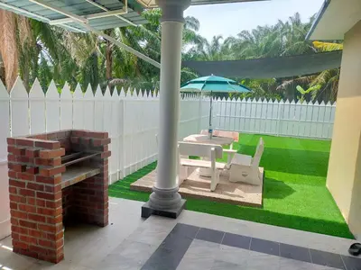 a patio with an umbrella and a table and a bench at Villa Auliyya - MusleemHomestay in Kampong Sungai Leman