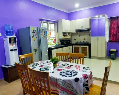 a kitchen with a table and a refrigerator at Villa Auliyya - MusleemHomestay in Kampong Sungai Leman