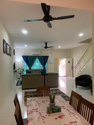 a living room with a table and a ceiling fan at ZillQayyim Homestay in Seri Iskandar