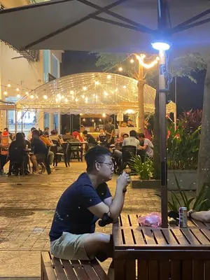 a man sitting on a bench at a restaurant at NEW 6Pax SOHO Near USM & SPICE ARENA & AIRPORT in Bayan Lepas