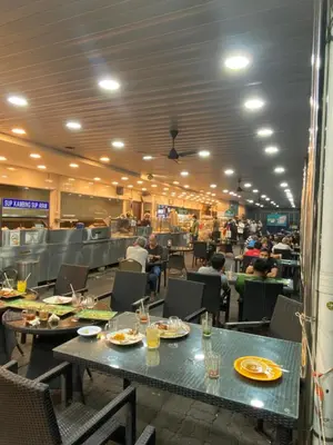 a dining room with tables and people sitting in chairs at NEW 6 PAX SUITE near USM and SPICE ARENA and AIRPORT in Bayan Lepas