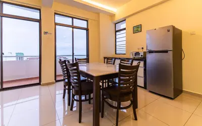 a dining room with a table and a refrigerator at Batu Ferringhi Sea View Penthouse Resort Home in Bayan Lepas