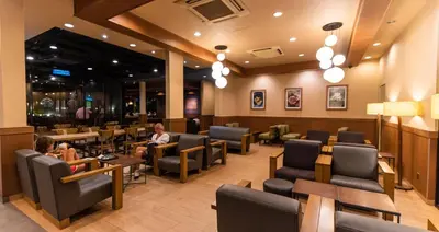 a waiting room with people sitting at tables and chairs at Batu Ferringhi Sea View Penthouse Resort Home in Bayan Lepas