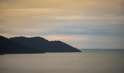 a large body of water with mountains in the distance at Batu Ferringhi Sea View Penthouse Resort Home in Bayan Lepas