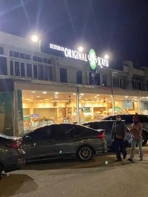 two people standing in front of a restaurant at night at 6PAX 1 BEDROOM SOHO Near USM SPICE ARENA PANTAI SPECIALIST AIRPORT in Bayan Lepas