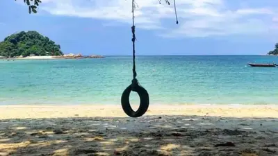 a tire swing hanging from a tree on a beach at Pangkor Pasir Bogak Apartment 2Rooms 2Bathrooms near beach 6pax FREE WIFI in Pangkor