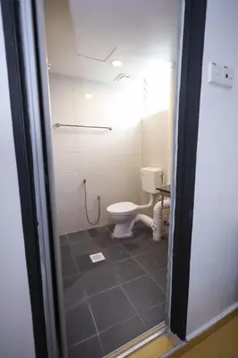 a bathroom with a toilet and a tiled floor at RENTIO HOTEL in Kulim