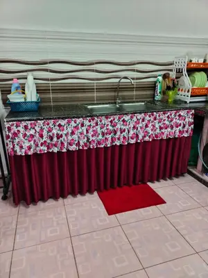 a kitchen counter with a red curtain and a sink at Rizki Homestay in Nibung Tebal