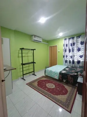 a bedroom with green walls and a bed with a rug at Rizki Homestay in Nibung Tebal