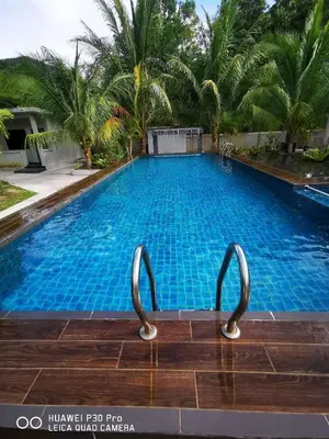 a large swimming pool with palm trees in the background at Pangkor Nature View House in Pangkor