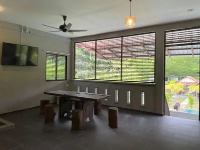 a dining room with a table and some windows at Pangkor Nature View House in Pangkor