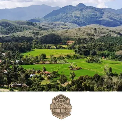 a view of a green field with mountains in the background at Tanah Merah Glamping Village (TMGV) in Kuala Kangsar