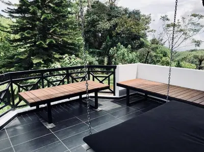 a swing and a bench on a balcony with trees at 80 Colonie Fraser's Hill 4pax in Bukit Fraser