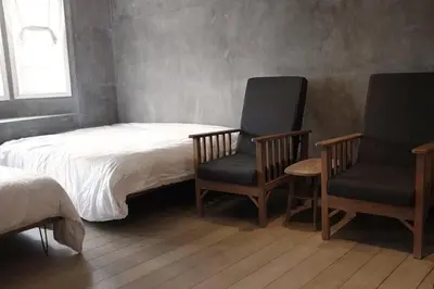 a bedroom with two chairs and a bed and a window at 80 Colonie Fraser's Hill 4pax in Bukit Fraser
