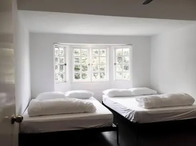 two beds in a white room with two windows at 80 Colonie Fraser's Hill 16 Pax in Bukit Fraser