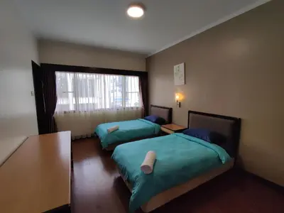 a room with two beds and a table and a window at Awesome Homestay Apartment @ Equatorial Hill Resort in Brinchang