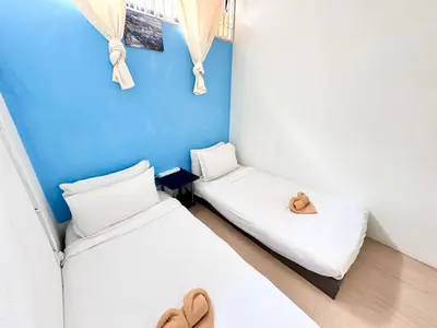two beds in a room with a blue wall at Mac Inn 94 in George Town
