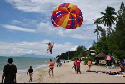 a person jumping into the air with a parachute on a beach at Batu Ferringhi Luxury Seaview Suite - 3Br in Batu Ferringhi