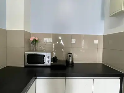 a kitchen with a microwave and flowers on a counter at Blue Aesthetic Luxury Seaview 3 min Drive Sunway in Butterworth