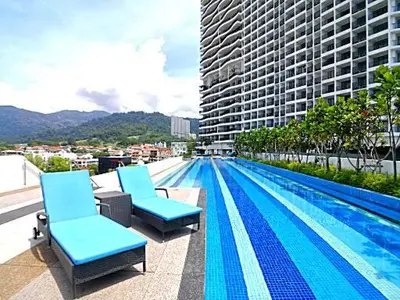 a swimming pool with two chairs and a building at Deluxe Seaview Suite Twin Bed by The Only Bnb in Tanjong Tokong