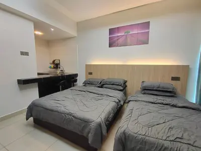 a bedroom with two beds and a desk and a counter at Alish Studio Apartment with Pool, Netflix, Wifi in Gua Musang