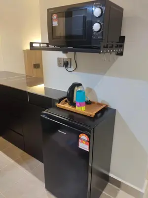 a small black refrigerator with a tv on top of it at Alish Studio Apartment with Pool, Netflix, Wifi in Gua Musang