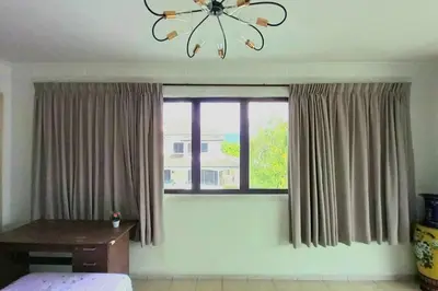 a bedroom with a window with curtains and a chandelier at 5 Bedroom 2 Bathrooms End-lot House, 3 parkings - Ipoh, Tambun in Ipoh