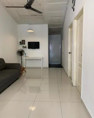 a living room with a couch and a tv on a wall at Jasmine Homestay Meru Ipoh in Ipoh