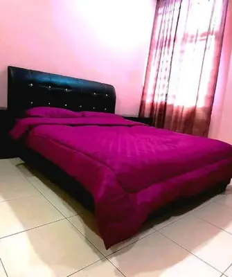 a bed in a room with a purple comforter at Grand Homestay Kulim 4-Bedroom in Lunas