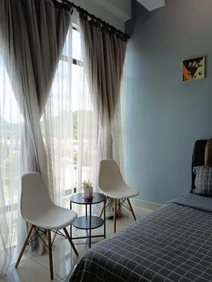 a bedroom with two chairs and a bed and a window at Armada Sweet Homestay in Gua Musang