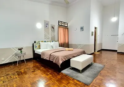 a bedroom with a large bed and a white chair at Advent Villa, just 80 meters to Penang Adventist Hospital in George Town