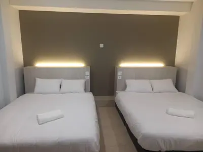 two beds with white sheets in a room at The Great Hotel in Ipoh