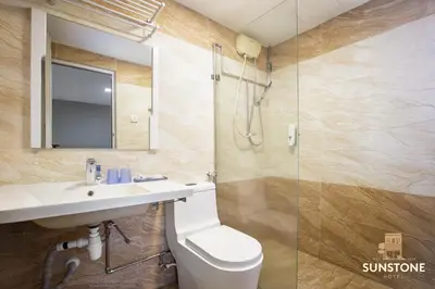 a bathroom with a toilet and a sink and a shower at Sunstone Hotel in George Town