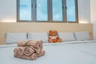 a teddy bear sitting on a bed with towels at Ipoh Tambun Lost World Sunway Onsen Suites Luna 2R2B 8paxs in Ipoh