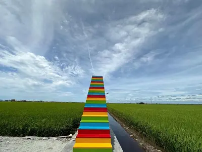 a rainbow striped stairway in the middle of a field at PADI Sentral @ Sekinchan in Sekincan
