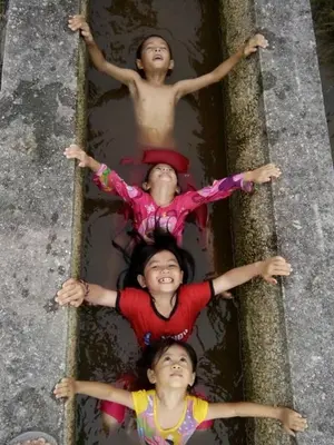 three children are laying in a pool of water at Purple Pool Villa in Kampong Batu Dua Puloh Tiga
