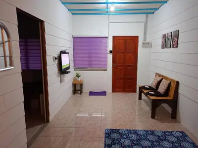 a hallway with a door and a chair and a television at Purple Pool Villa in Kampong Batu Dua Puloh Tiga