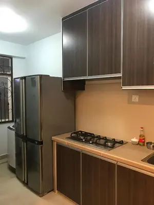 a kitchen with wooden cabinets and a stainless steel refrigerator at The Rockview Bayu Emas Penang Near Beach in Batu Ferringhi