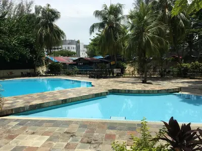 a large blue swimming pool with palm trees in the background at The Rockview Bayu Emas Penang Near Beach in Batu Ferringhi
