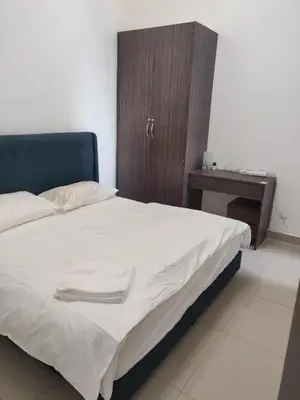 a bedroom with a bed with white sheets and a table at Mars Homestay in Kea Farm Brinchang in Brinchang