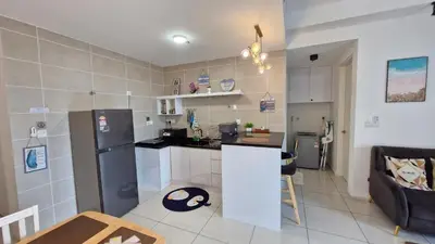 a kitchen and living room with a refrigerator and a counter at H&W Sunway Onsen Suite 4-7pax near Lost World of Tambun Ipoh in Ipoh