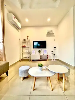 a living room with two tables and a tv at Ipoh Deluxe Family Home in Ipoh