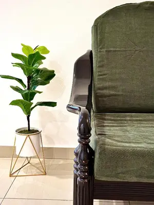 a green chair with a potted plant next to it at Ipoh Deluxe Family Home in Ipoh