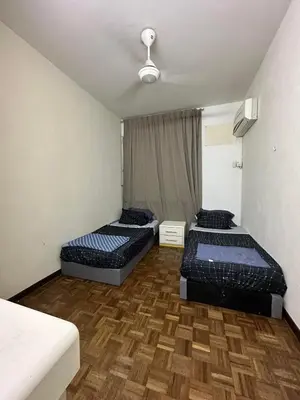 a bedroom with two beds and a wooden floor at Bayu Emas Ferringhi Homestay in Batu Ferringhi