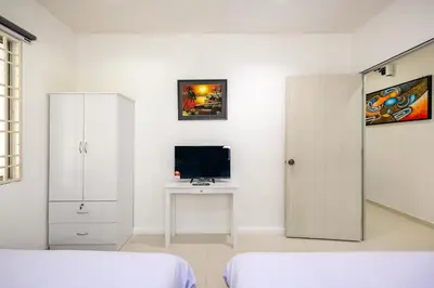 a white bedroom with a desk and a tv at Seaside Private Bungalow, Tg Bungah in Tanjung Bungah